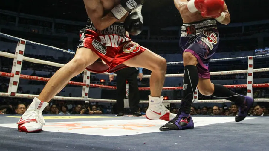 Boxer practicing quick footwork drills on an agility ladder in the gym