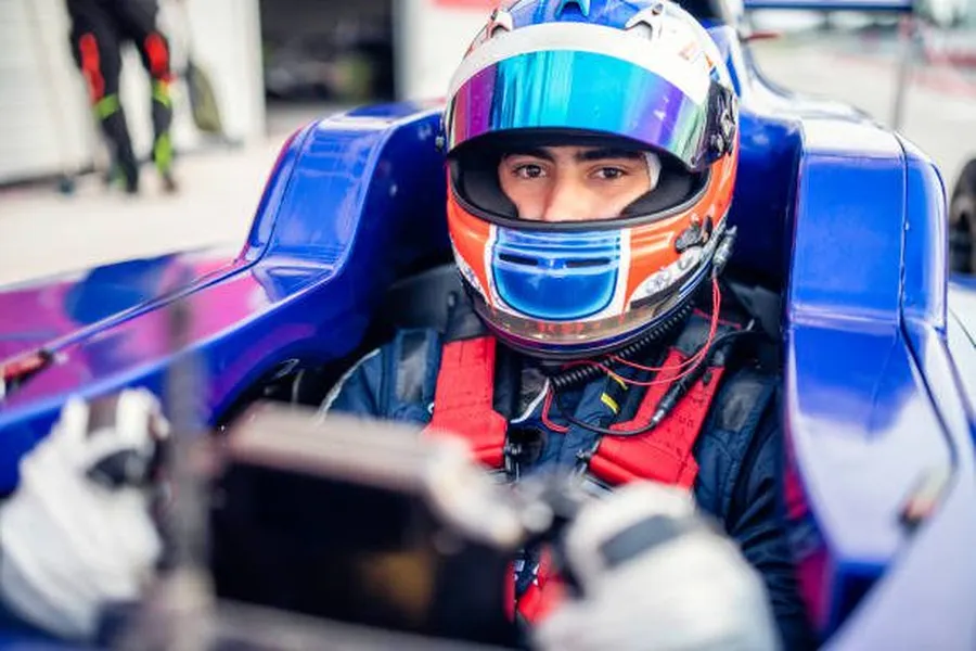 Young driver in racing suit next to race car